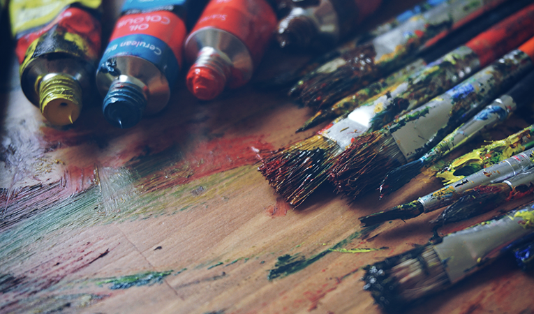 paints and brushes laid out on a wood palette