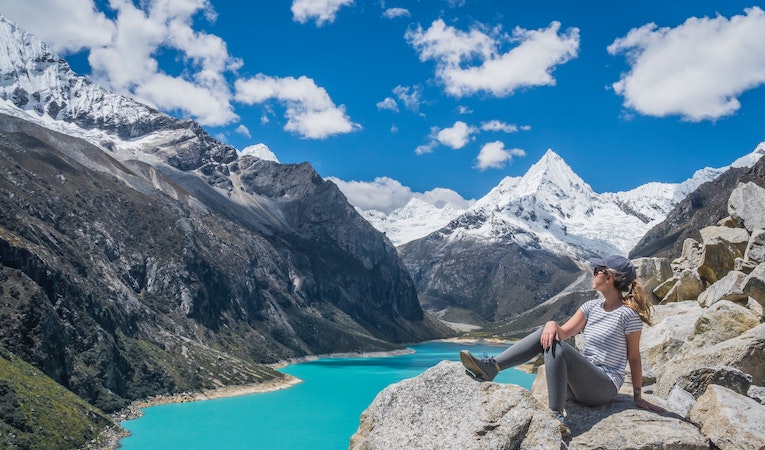 person sitting on a rock overlooking a glacial lake