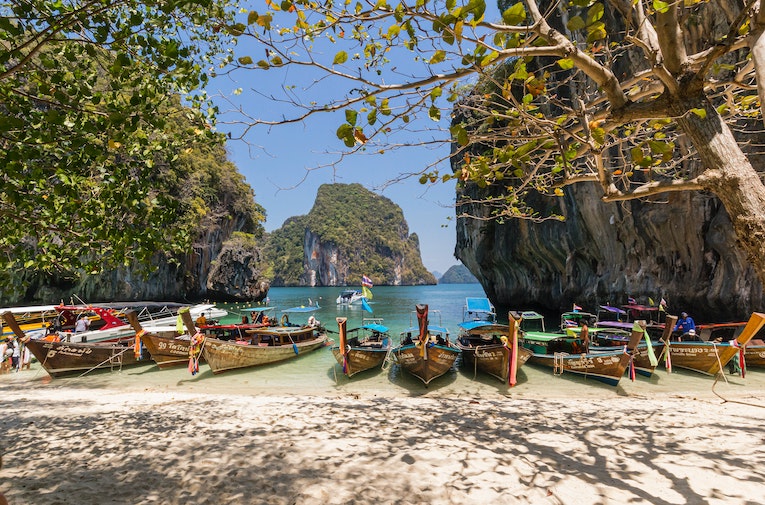 Wooden boats line the seashore on a beach in Thailand