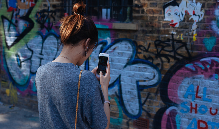 girl taking photo of street art in London