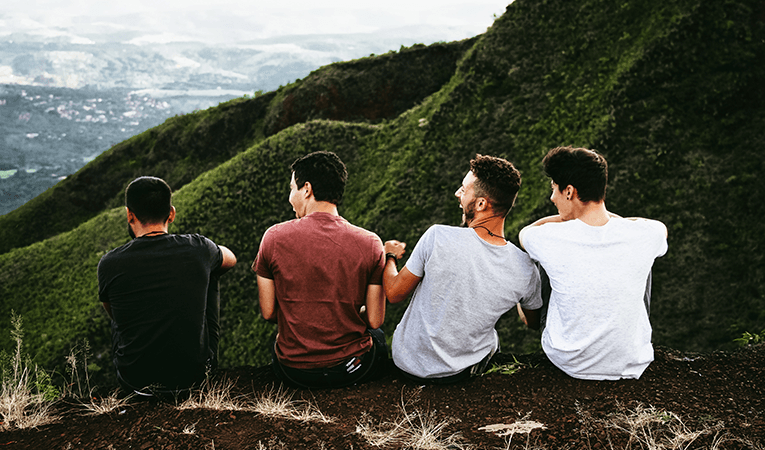boys laughing looking out on green valley on mountainside