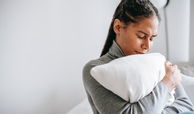 distressed person hugging a pillow