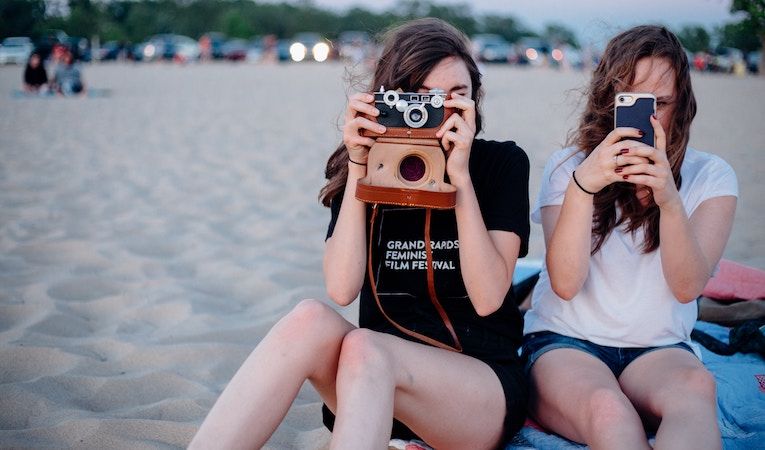 teen girls on a beach taking photos