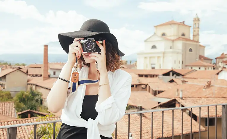 woman in black hat snapping a photo with a film camera