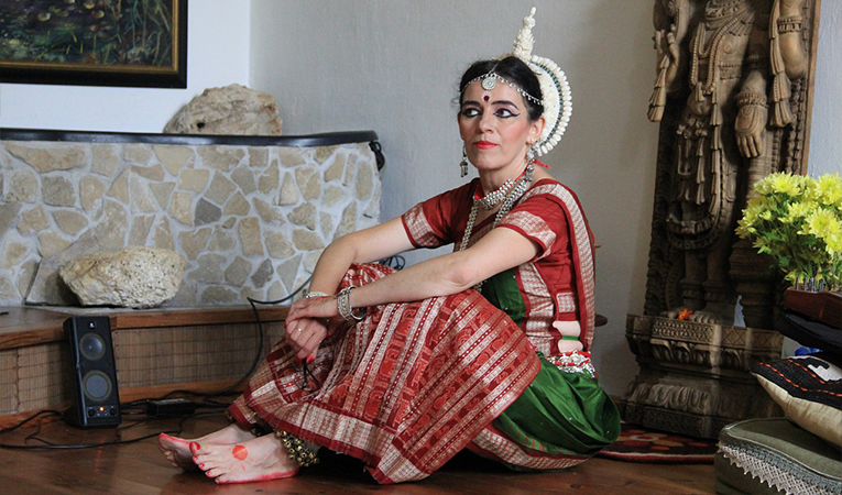 Woman in traditional Indian dance costume with her hands painted in henna
