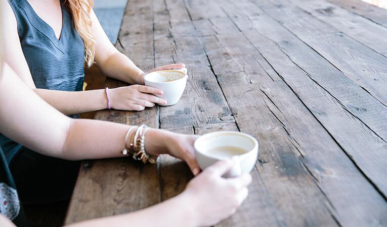 two people sitting while having a cup of cappuccino