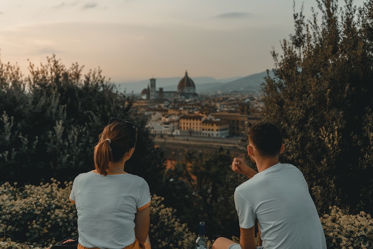 two people sitting near green trees overlooking Florence architecture in the background