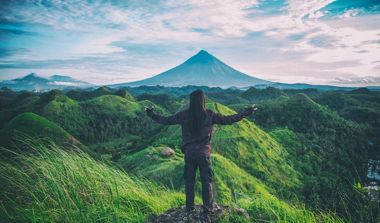 person posing on hilltop near mayon volcano philippines