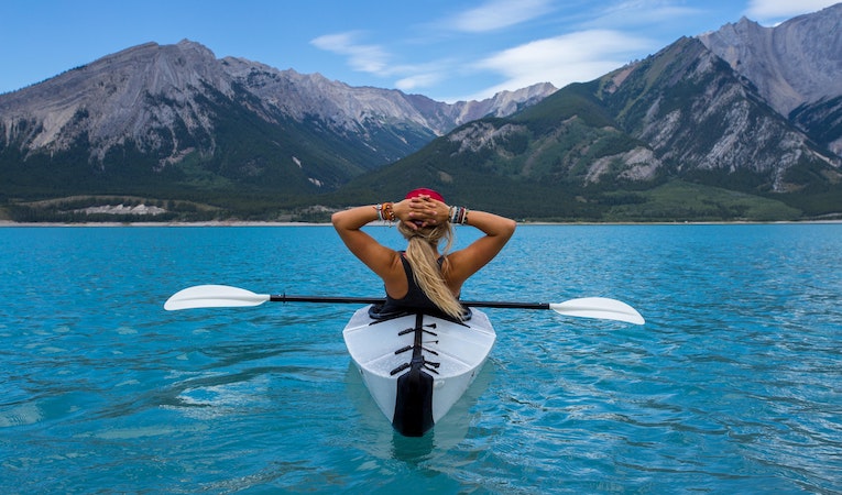 person on kayak looking at mountains in Canada