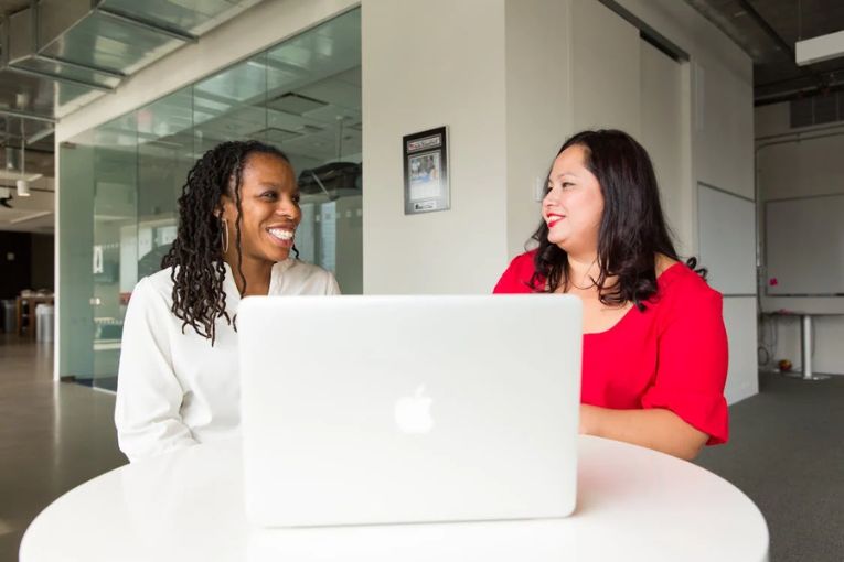 two people discussing something with a laptop in front of them