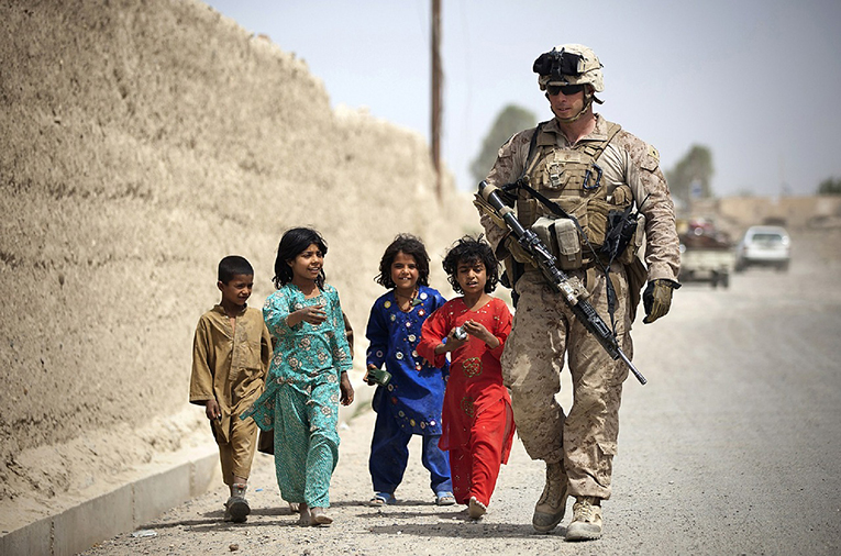 Solider walking with children in the Middle East