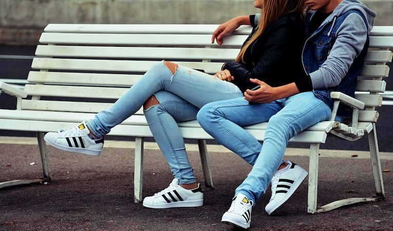 boy and girl sitting on park bench with cool shoes on