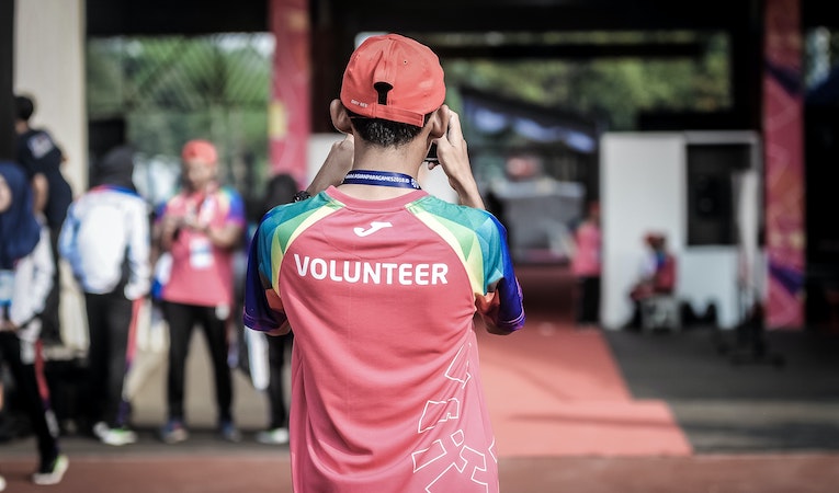 person wearing a colorful volunteer shirt and cap