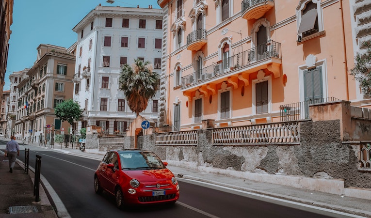 View of colorful Italian buildings and a red Fiat driving on the street