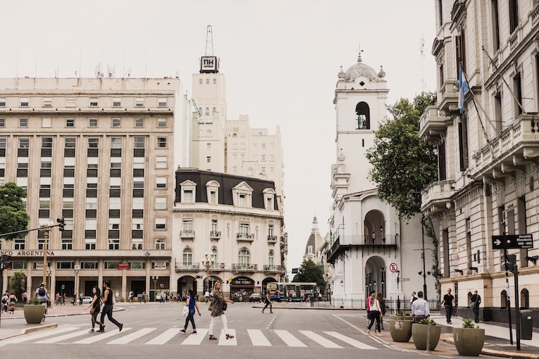 pedestrians crossing street with buildings in Buenos Aires in the background