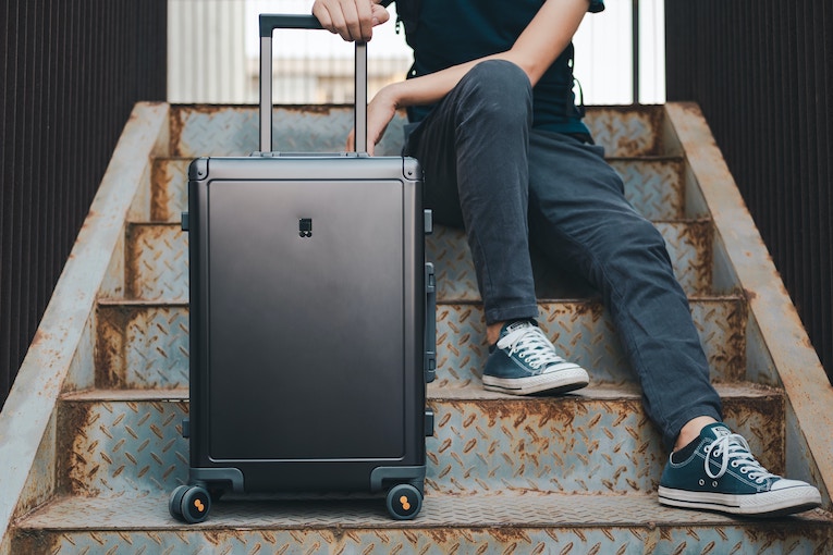 lower half of person sitting on stairs with suitcase