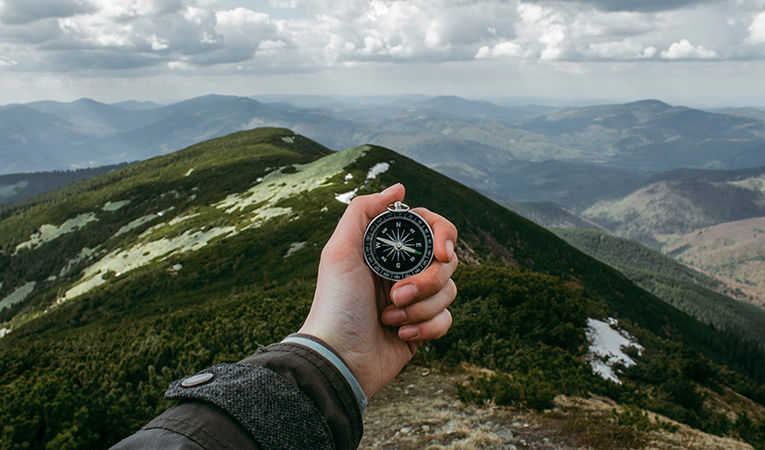 holding out compass over mountains