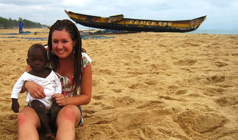 Volunteer holding a baby on a beach
