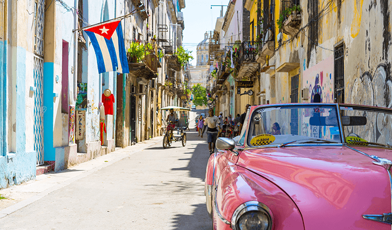 Pink hot rod on old road with cuban flag